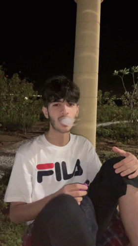 Young Man in White Fila T-Shirt Smoking Cigarette