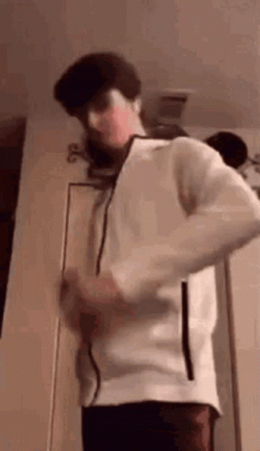 Young Man In White Jacket Standing In Front Of Door GIF