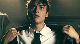 Young Man in White Shirt and Black Tie Adjusting Jacket