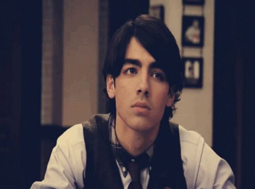 Young Man In White Shirt And Brown Vest GIF