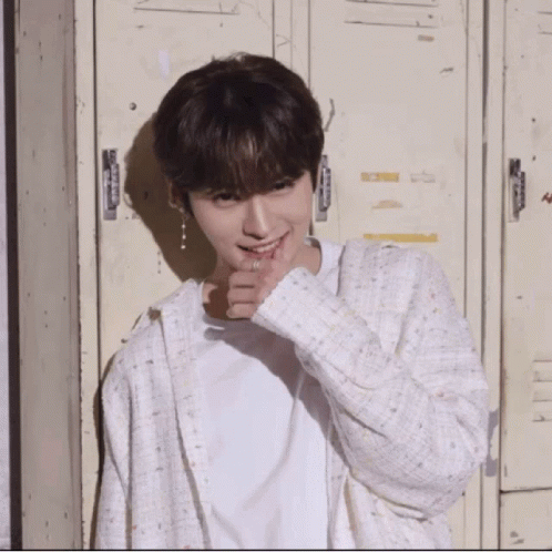 Young Man in White Shirt and Cardigan in Front of Lockers Smiling