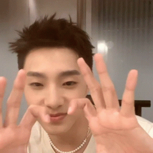 Young Man in White Shirt and Pearl Necklace Making Peace Sign