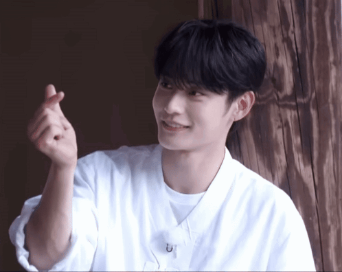Young Man in White Shirt Making Heart with Hands