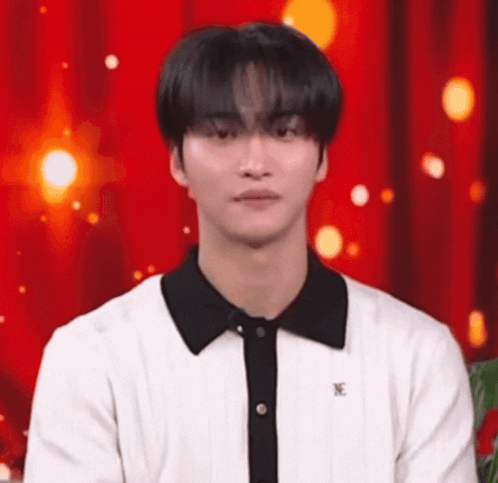 Young Man in White Shirt With Black Collar in Front of Red Curtain