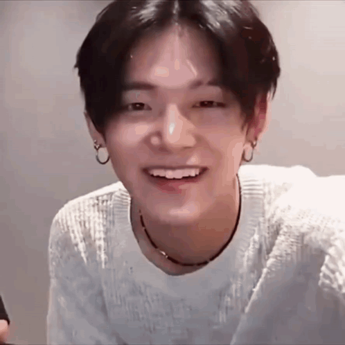 Young Man in White Sweater and Black Necklace Smiling