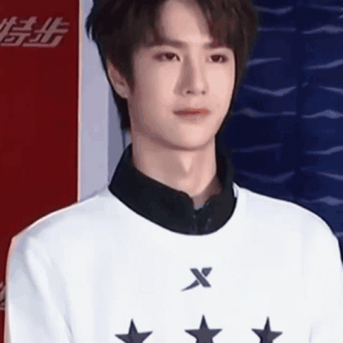 Young Man In White Sweater With Stars Against Red And Blue Wall GIF
