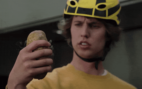 Young Man in Yellow Helmet Holding Potato