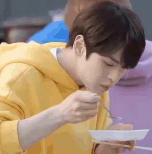 Young Man in Yellow Hoodie Eating with Chopsticks