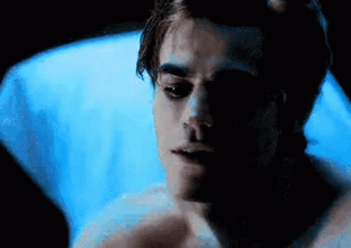 Young Man Laying in Bed With Blue Blanket