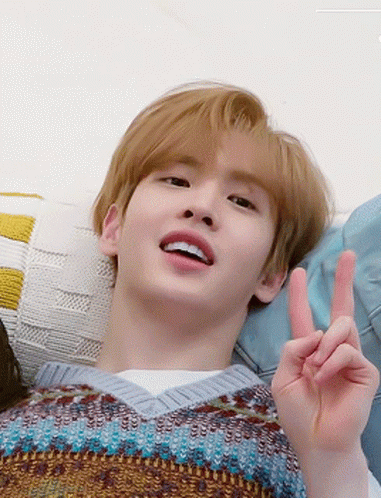 Young Man Laying on Couch Making Peace Sign