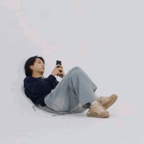Young Man Laying on Floor Looking at Phone