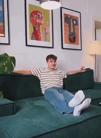 Young Man Lying on Green Couch Arms Outstretched