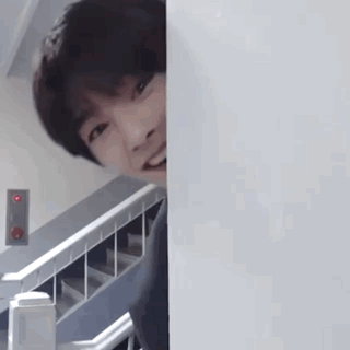 Young Man Peeking Behind Wall