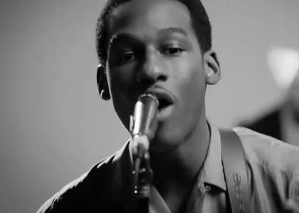Young Man Singing Into Microphone Playing Saxophone