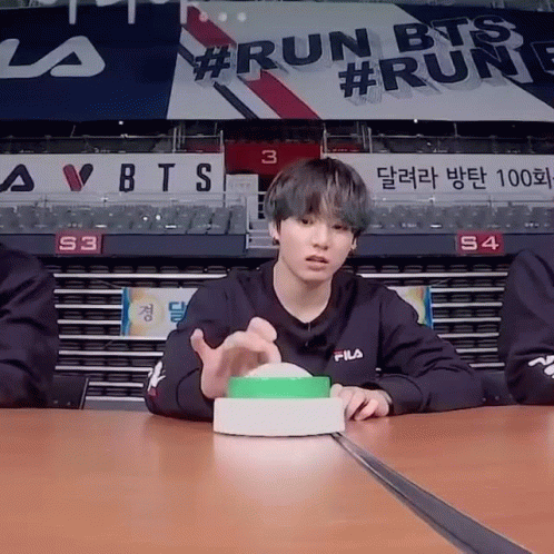 Young Man Sitting at Table With Run BTS Sign