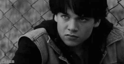 Young Man Sitting by Chain Link Fence