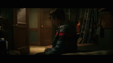 Young Man Sitting in Dark Room With Ladder
