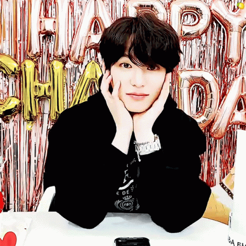 Young Man Sitting in Front of Happy Day Balloons