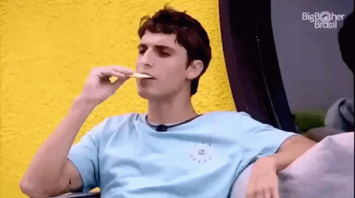 Young Man Sitting on Couch Eating Food
