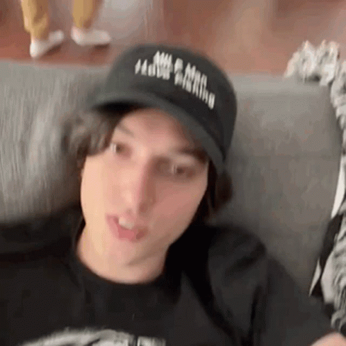 Young Man Sitting on Couch in Black Hat