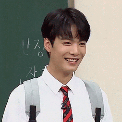 Young Man Smiling at Blackboard with Chinese Writing