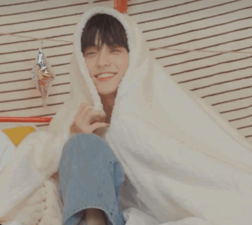 Young Man Smiling in White Blanket