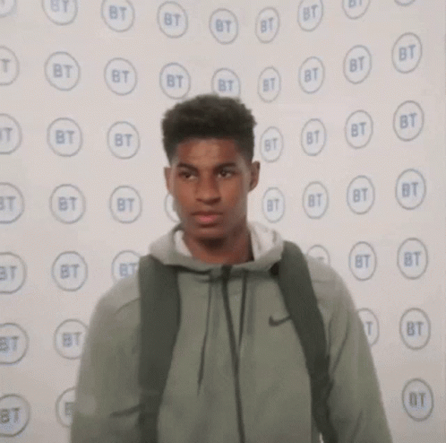 Young Man With Backpack Near BT Logos Wall GIF