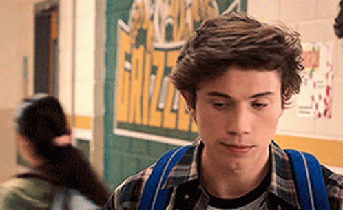 Young Man With Blue Backpack Walking Down Hallway