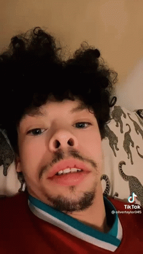Young Man With Curly Hair and Beard Laying on Bed