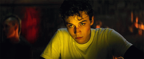 Young Man with Curly Hair and Yellow Eyes Looking at Camera