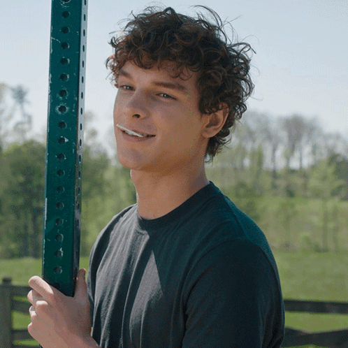 Young Man With Curly Hair Holding Green Pole