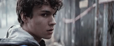 Young Man With Curly Hair in Grey Hoodie Looking at Camera