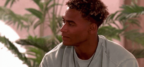 Young Man With Curly Hair In White Sweater And Necklace GIF
