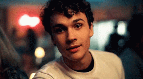 Young Man With Curly Hair Looking at Camera Blurry Background