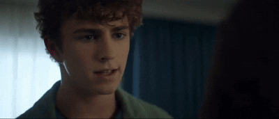 Young Man With Curly Hair Looking At Woman In Dark Room GIF