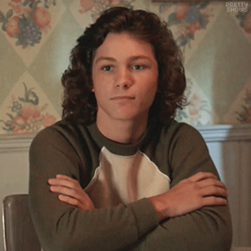 Young Man With Curly Hair Sitting Crossed Arms