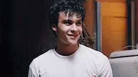Young Man With Curly Hair Smiling in White T-Shirt
