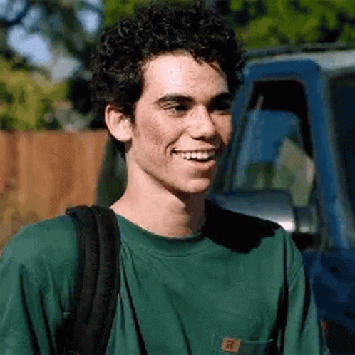 Young Man With Curly Hair Smiling Next To Blue Truck