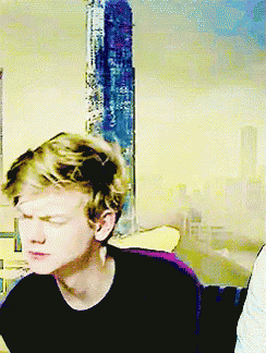 Young Man With Eyes Closed Sitting In Front Of Yellow Wall GIF