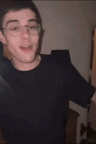Young Man With Glasses In Black Shirt Making Funny Face GIF