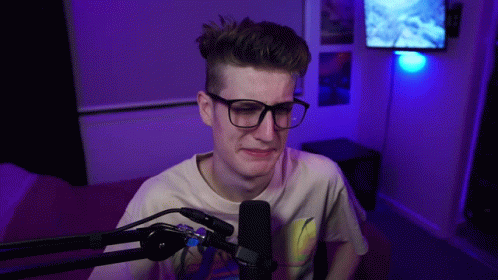Young Man with Glasses Sitting at Microphone