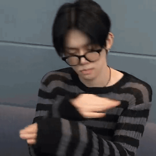 Young Man With Glasses Sitting in Striped Sweater
