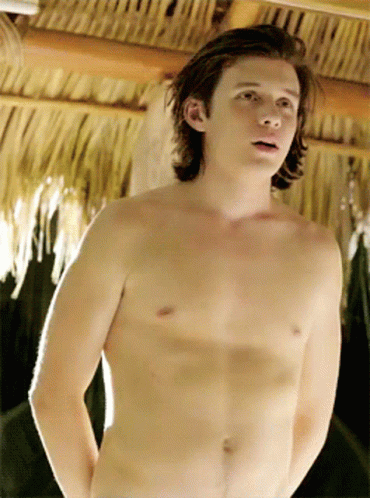 Young Man Without Shirt in Front of Thatched Roof