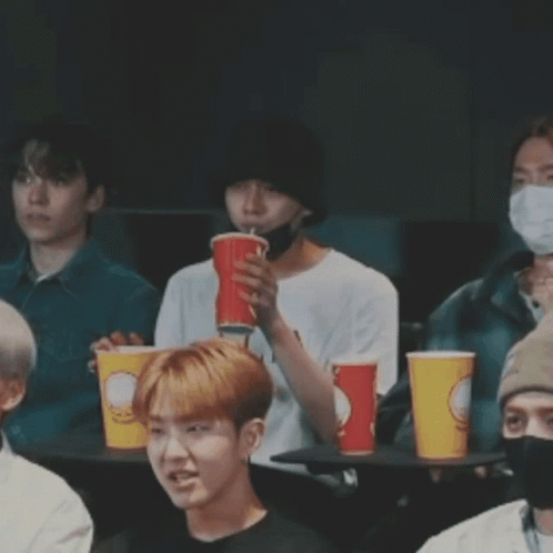 Young Men At Table With Cups, One Covering Mouth GIF