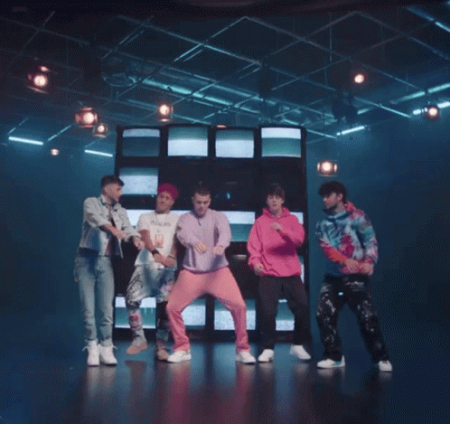 Young Men Dancing On Stage In Front Of Wall Of Televisions GIF