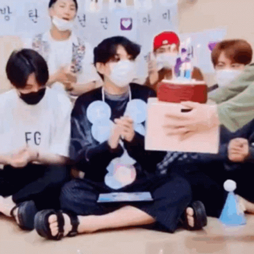 Young Men in Face Masks Holding Birthday Cake
