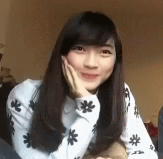 Young Woman Sitting On Bed With Hand On Face GIF