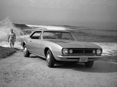A 1967 Chevy Camaro Is Parked On A Dirt Road Near The Ocean GIF