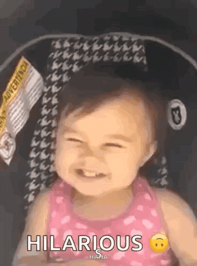 A Baby Girl Is Sitting In A Car Seat And Smiling With The Words Hilarious Written Next To Her . GIF