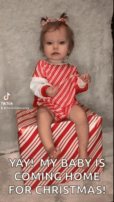 A Baby Girl Is Sitting On A Candy Cane Striped Box . GIF